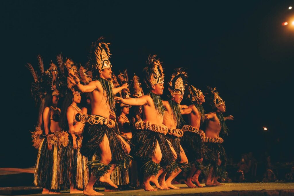 A group of performers in grass skirts dancing Tahitian on a stage